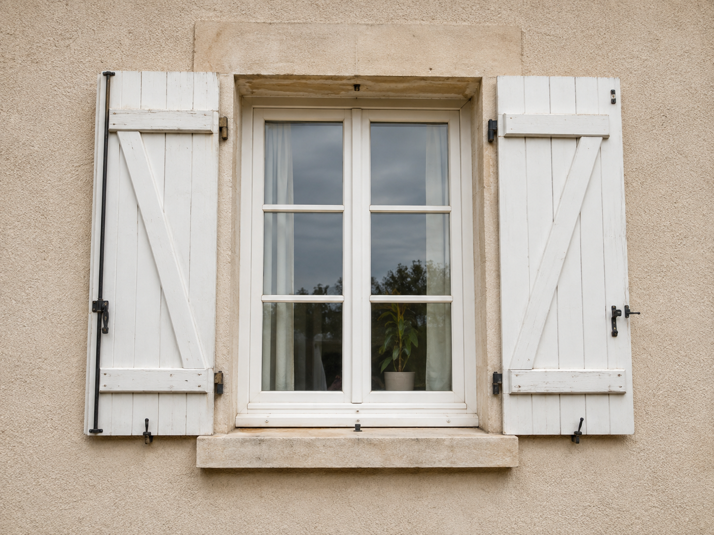 Anciens volets battants blancs installés autour d’une fenêtre
